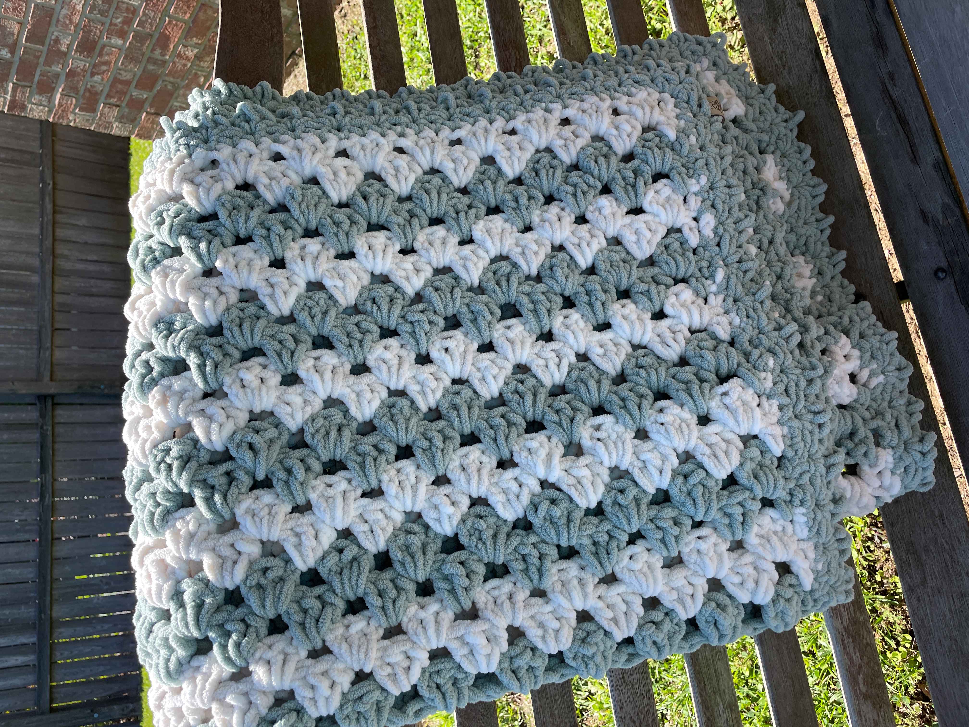 Speedy Granny Stripe Blanket in stripes of Misty Green and Beach Foam with a Misty Green Border hanging on a swing